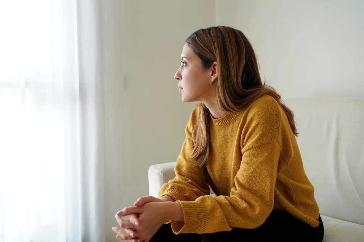 Working through difficult life situations with therapy at WellMind - woman feeling sad looking out the window